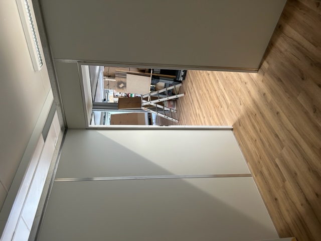 Blick aus einer leeren Lagerbox mit Holzboden und Deckenbeleuchtung in die Halle in Bretzenheim/Nahe